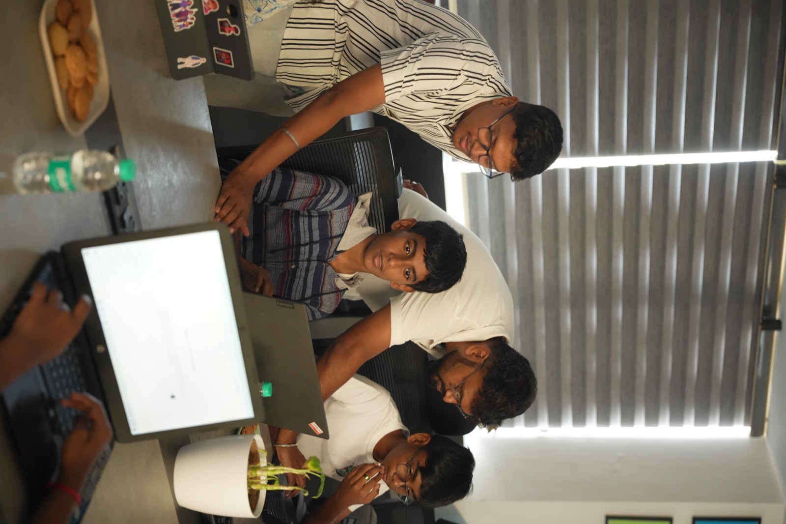 Students working closely with a Rewire mentor on a laptop